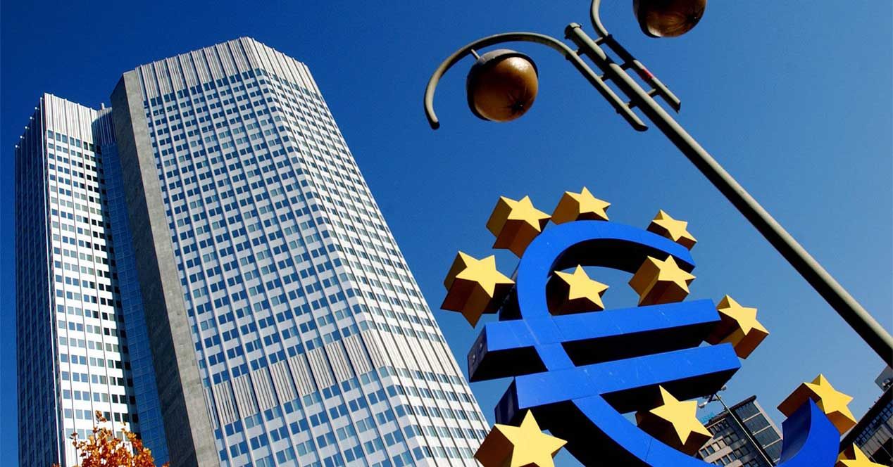 Símbolo del euro azul rodeado de estrellas amarillas frente a la torre del Banco Central Europeo en Fráncfort.