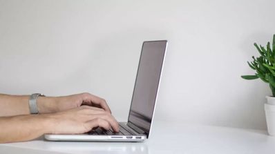 Las manos mientras está tecleando en un ordenador portátil