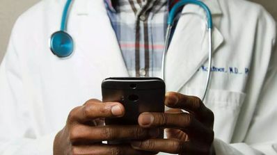 Un médico del hospital sujetando su teléfono móvil