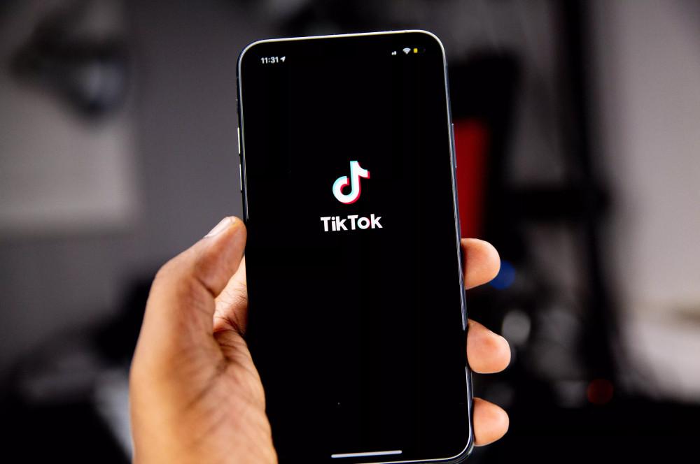 Alguien sostiene un teléfono móvil con la mano con el logotipo de TikTok.