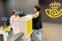 Una clienta siendo atendida por un empleado en el mostrador de una oficina de Correos para resolver una consulta