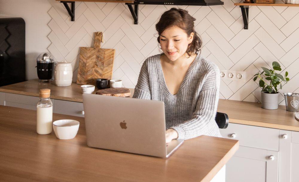 Mujer utilizando un ordenador Mac en la cocina