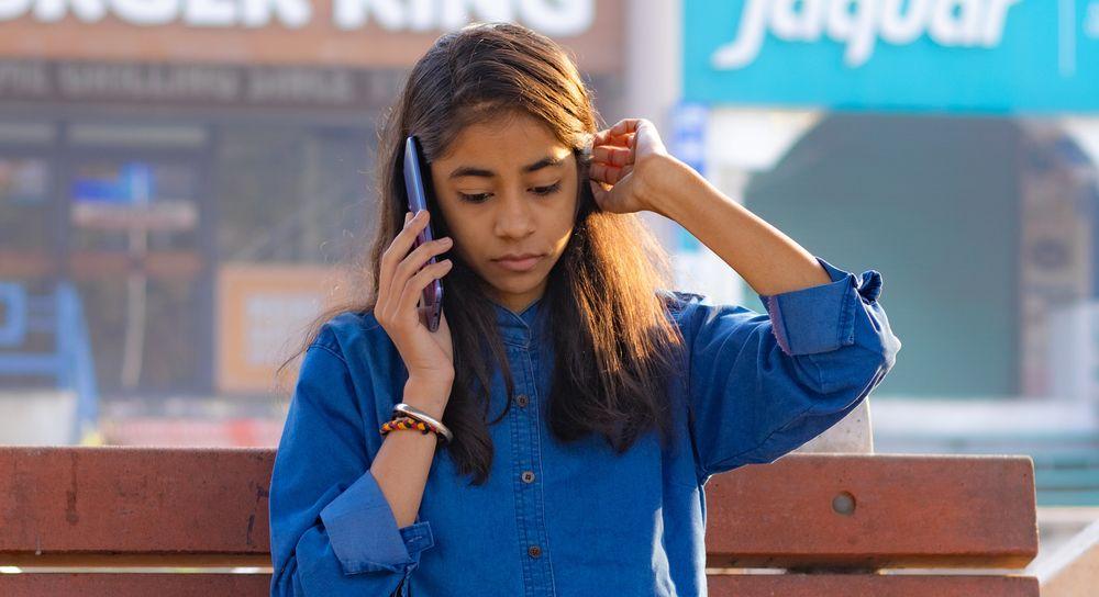 Chica preocupada habla con el móvil en la calle