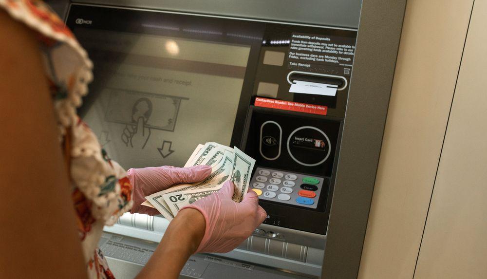 Una chica saca dinero en dólares en un cajero automático