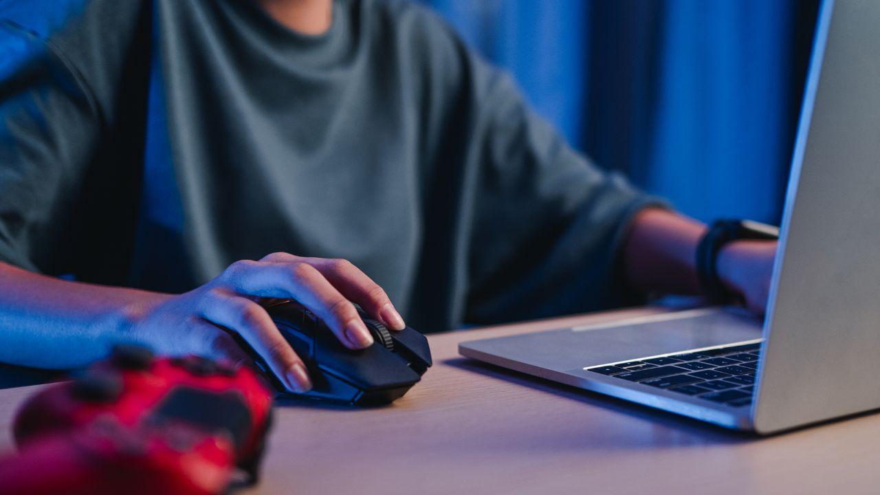 Una gamer usa el ratón para jugar en su ordenador portátil