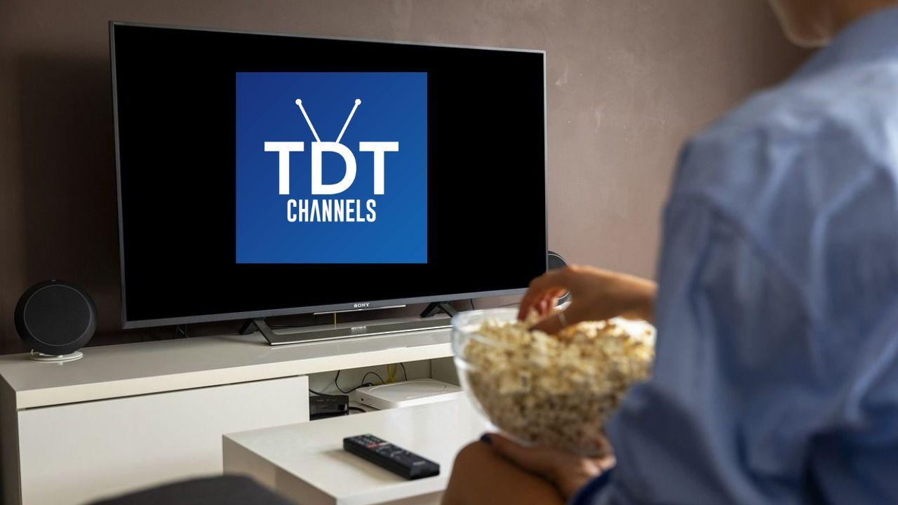 Un hombre sentado comiendo palomitas y viendo TDTChannels
