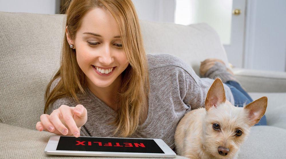 Una chica está con su perro cargando Netflix en su tablet