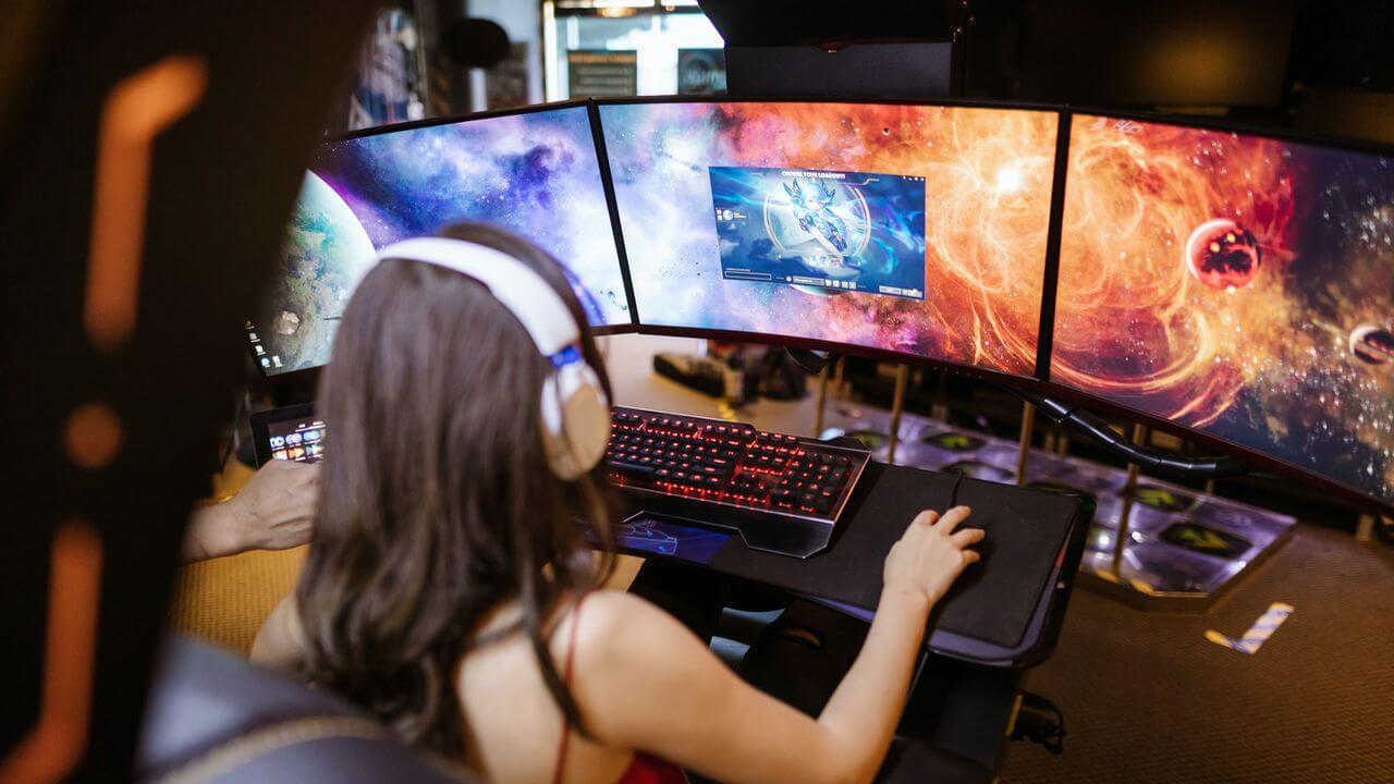 Chica jugando a un juego de ordenador en varias pantallas