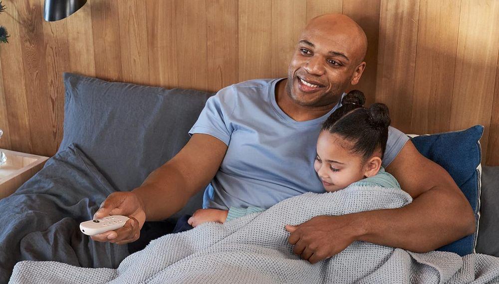 Padre e hija se divierten viendo la TV con un mando Chromecast