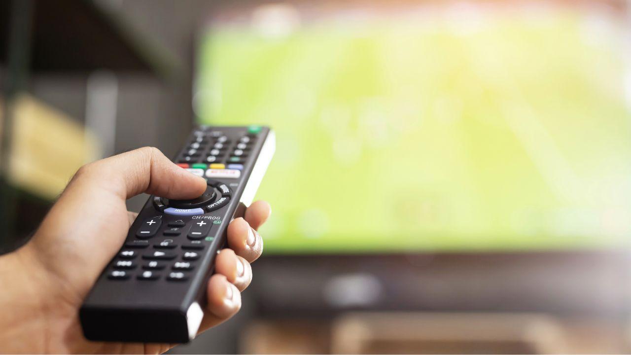 Sujetando el mando a distancia mientras ve deportes en la tele