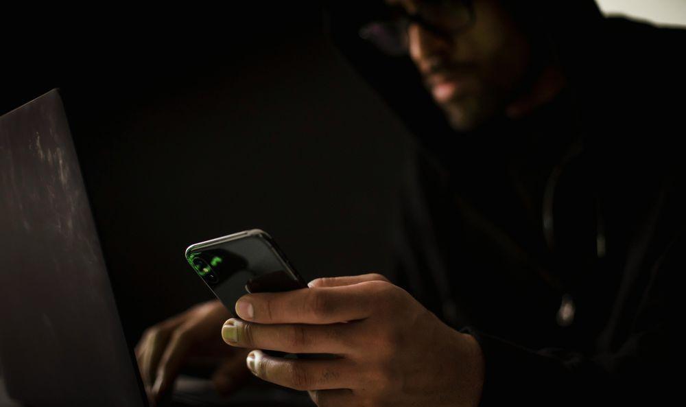 Un hacker usa su móvil y el ordenador para realizar un ataque