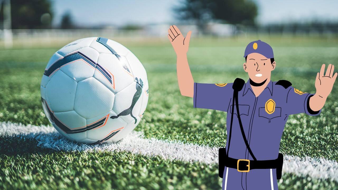 Una pelota de fútbol en el campo y un policía levantando los brazos