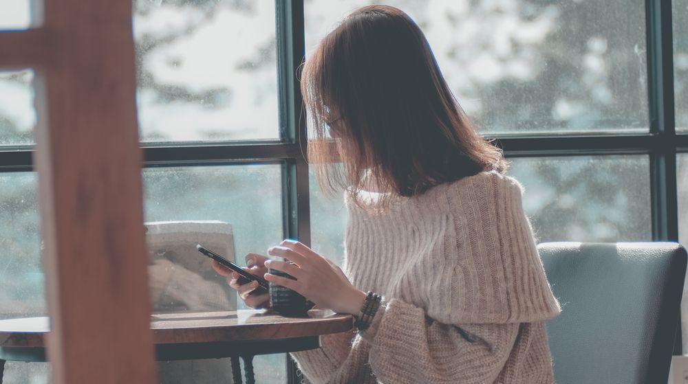 Una chica se toma un café mientras está mirando tiendas online con el móvil