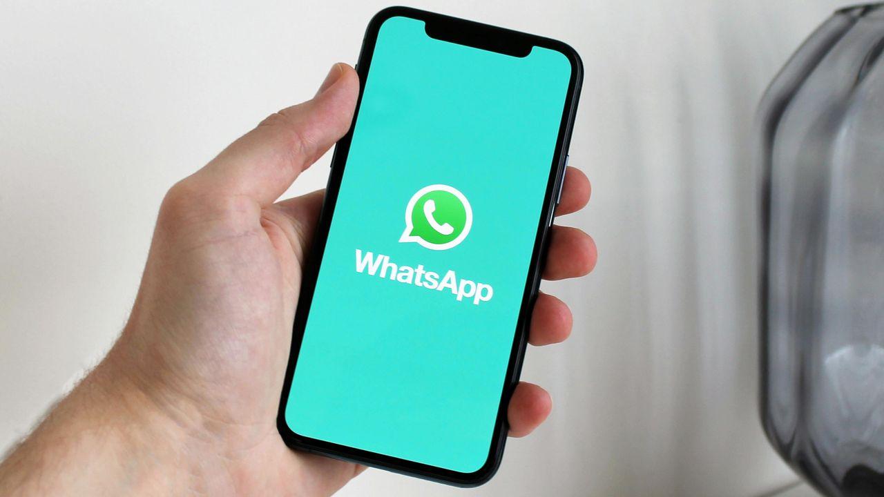 Un usuario sujeta su móvil con la aplicación de WhatsApp mientras carga