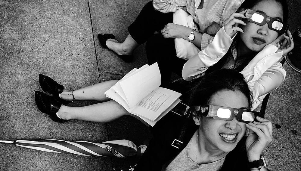 Unas chicas usan gafas para ver un eclipse solar total