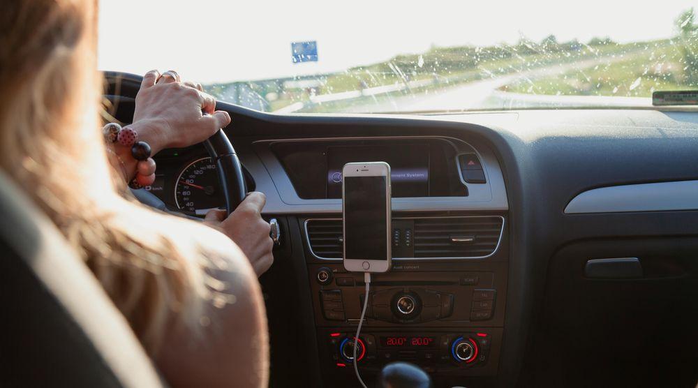 Una mujer lleva el móvil conectado en un coche sin pantalla táctil