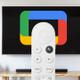 Un mando a distancia delante de una Smart TV con el logo de Google TV