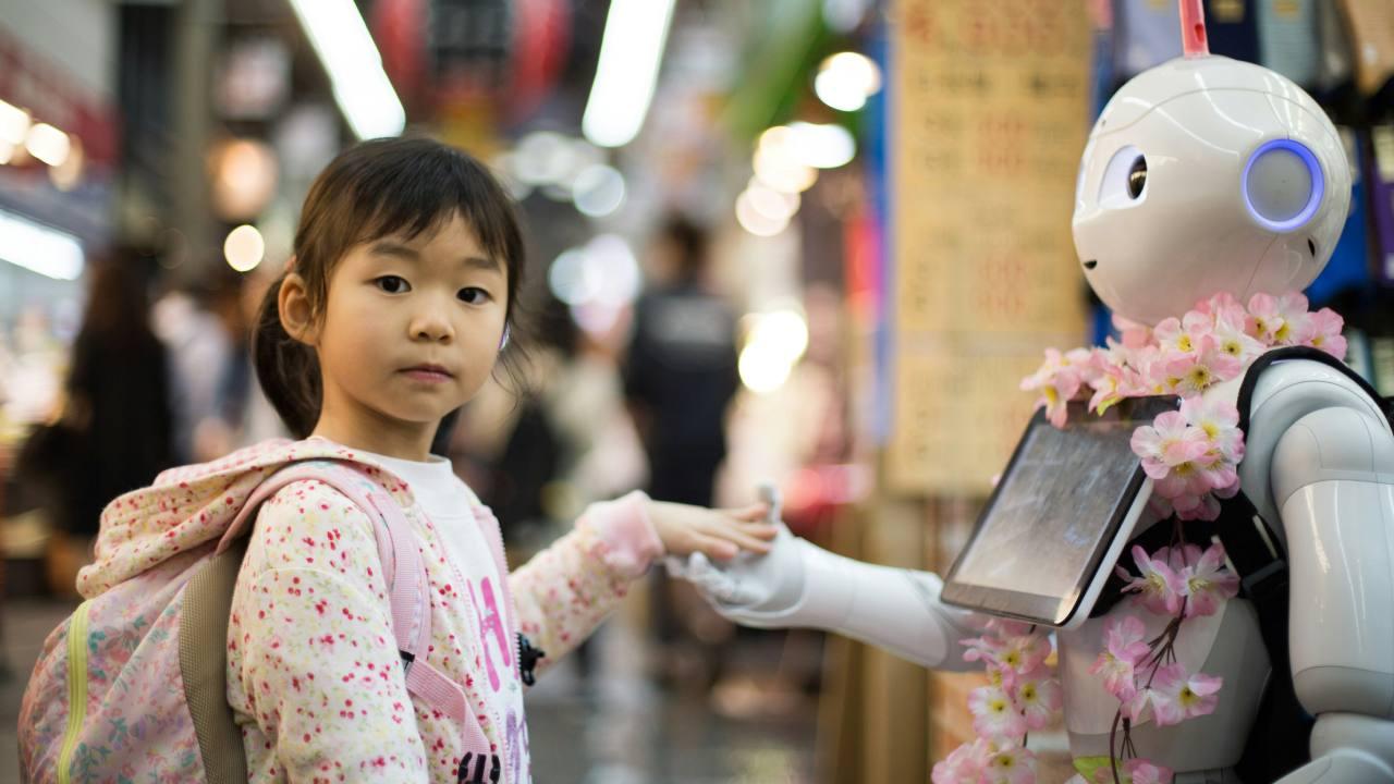 Una niña da la mano a un robot.