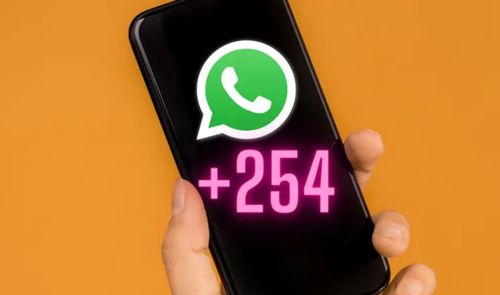 Mano sujetando un teléfono móvil que muestra el logotipo de WhatsApp y el prefijo telefónico +254 sobreimpresionados en la pantalla.