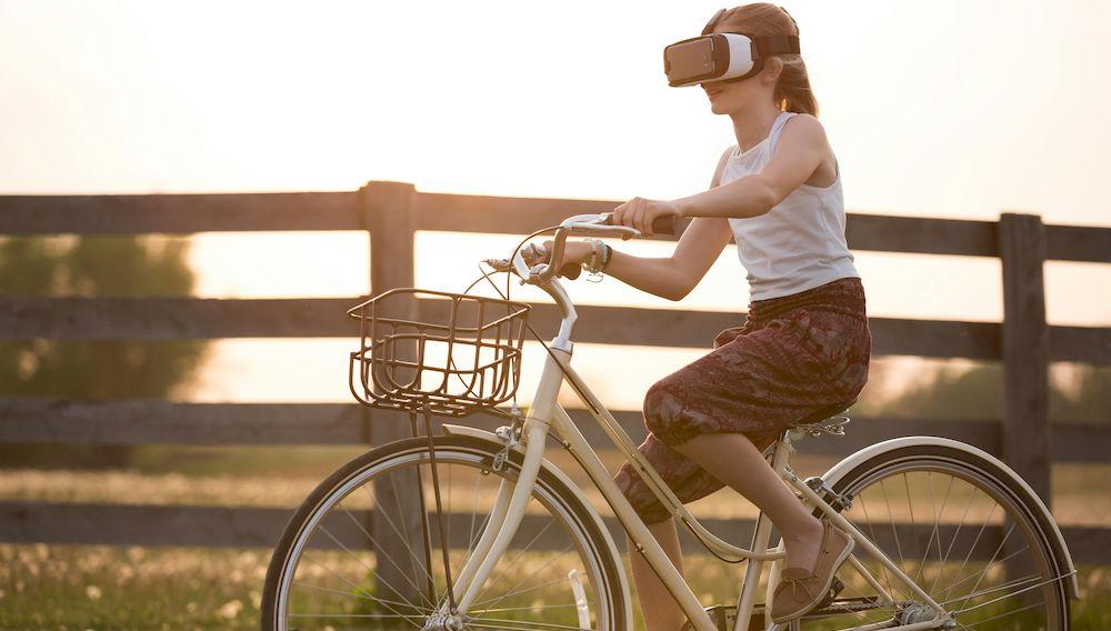 Una chica monta en bicicleta con unas gafas de realidad virtual