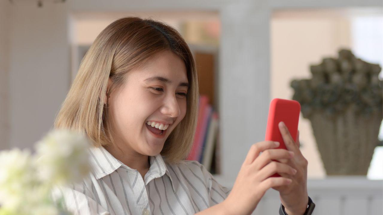 Una chica está feliz mientras descubre una buena noticia en el móvil