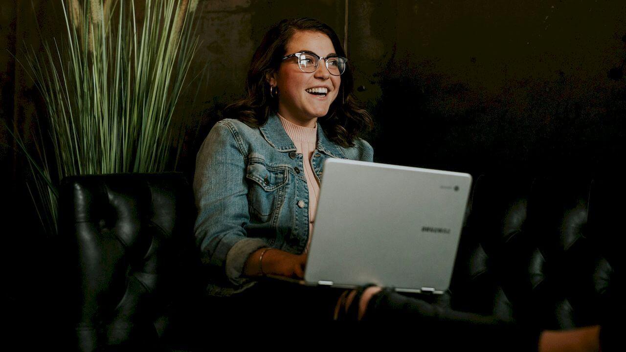 Una chica está feliz mientras utiliza su ordenador portátil