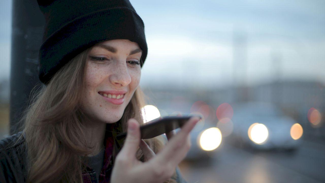 Una chica sujeta el móvil mientras habla con el manos libres