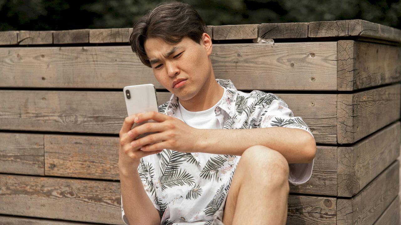 Un hombre descontento mira la pantalla de su teléfono móvil