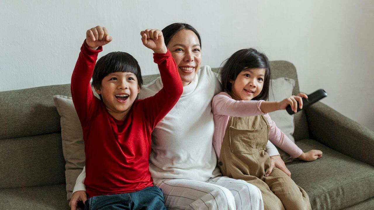 Una madre con sus hijos viendo la televisión muy felices