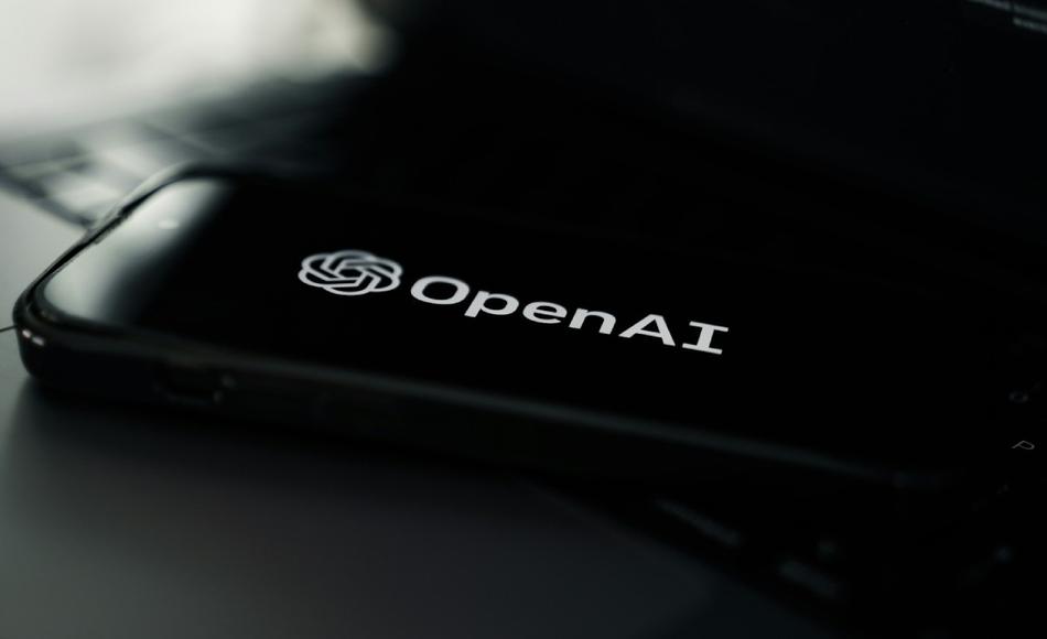 Logotipo de OpenAI mostrado en una pantalla de móvil, sobre un portátil con entorno oscuro.