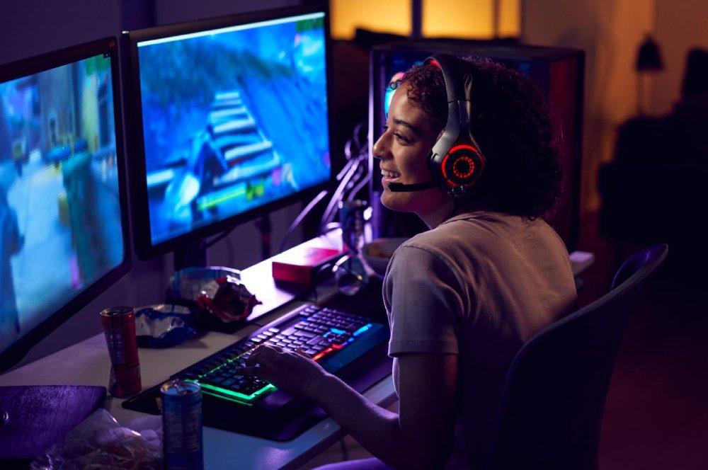 Una chica juega a videojuegos con dos pantallas.