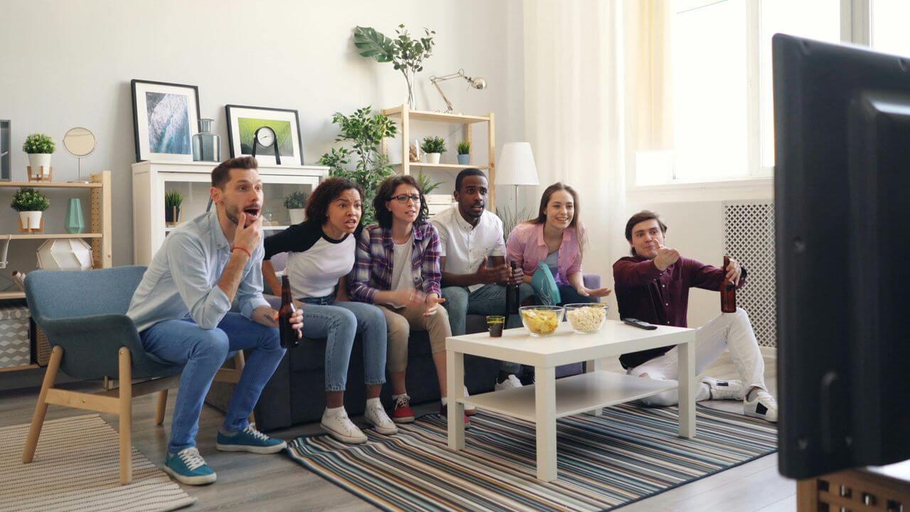Grupo de amigos viendo la televisión reunidos y sorprendidos