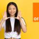 Una chica contenta enseña las manos y el logo de Orange