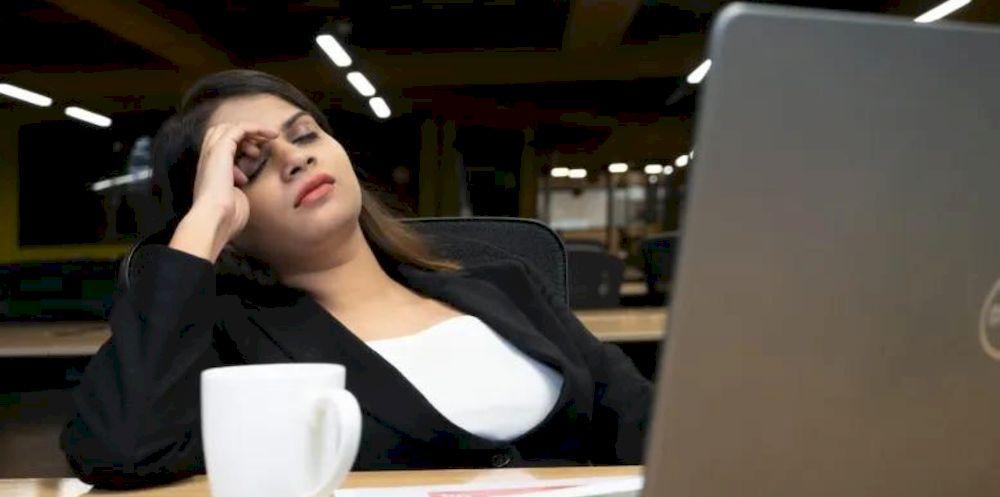 Una chica medio dormida delante del ordenador portátil