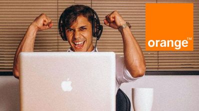 Un chico con auriculares y ordenador Apple celebrando una noticia