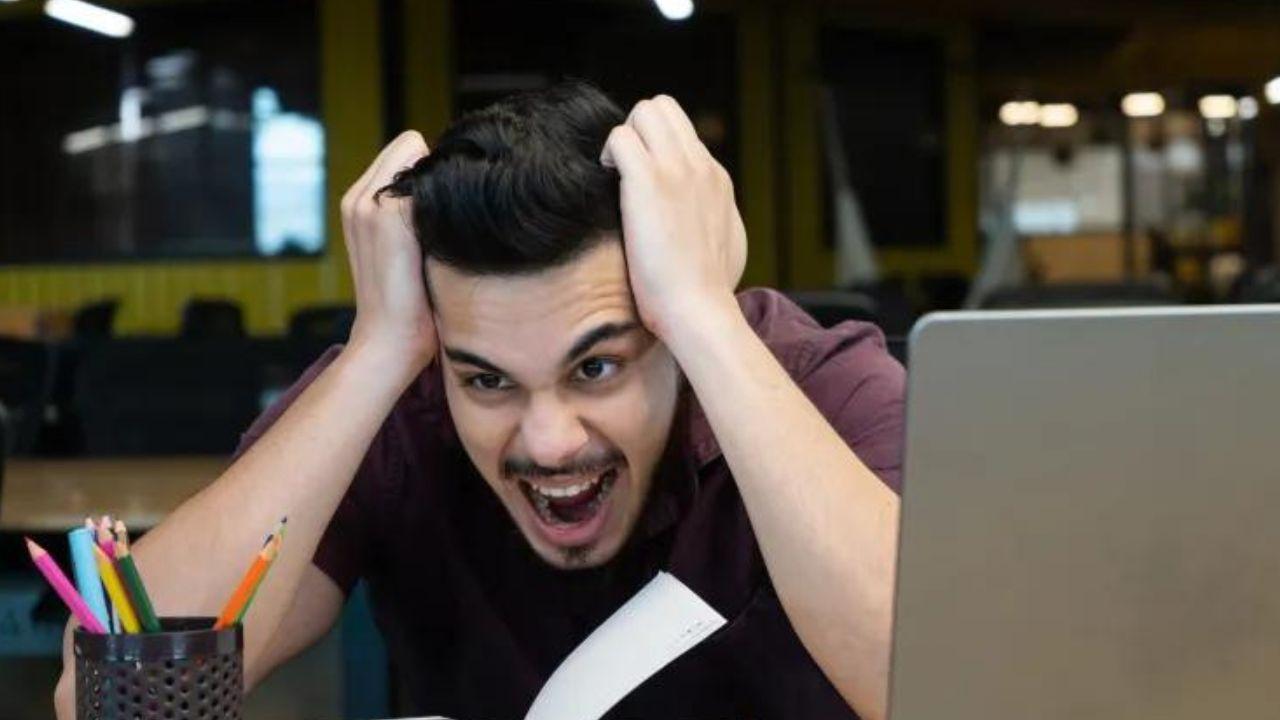 Un hombre grita de rabia delante de su ordenador portátil