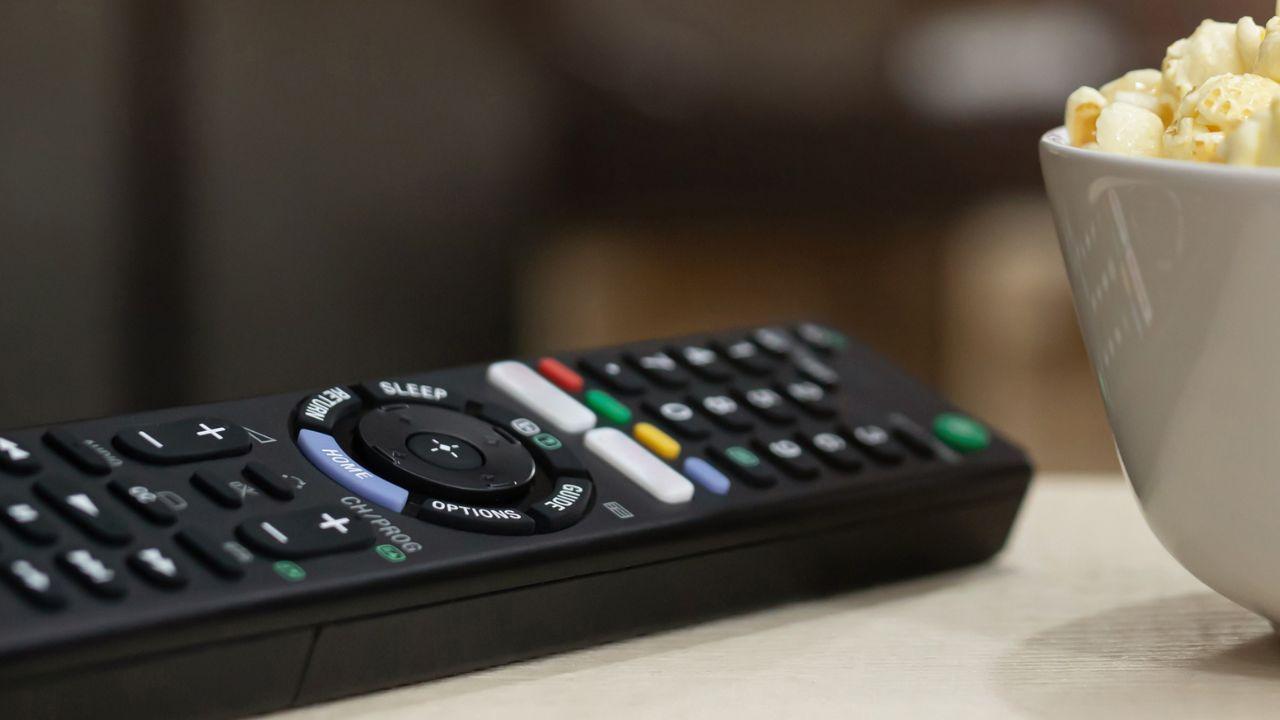 Un mando a distancia de color negro junto a palomitas