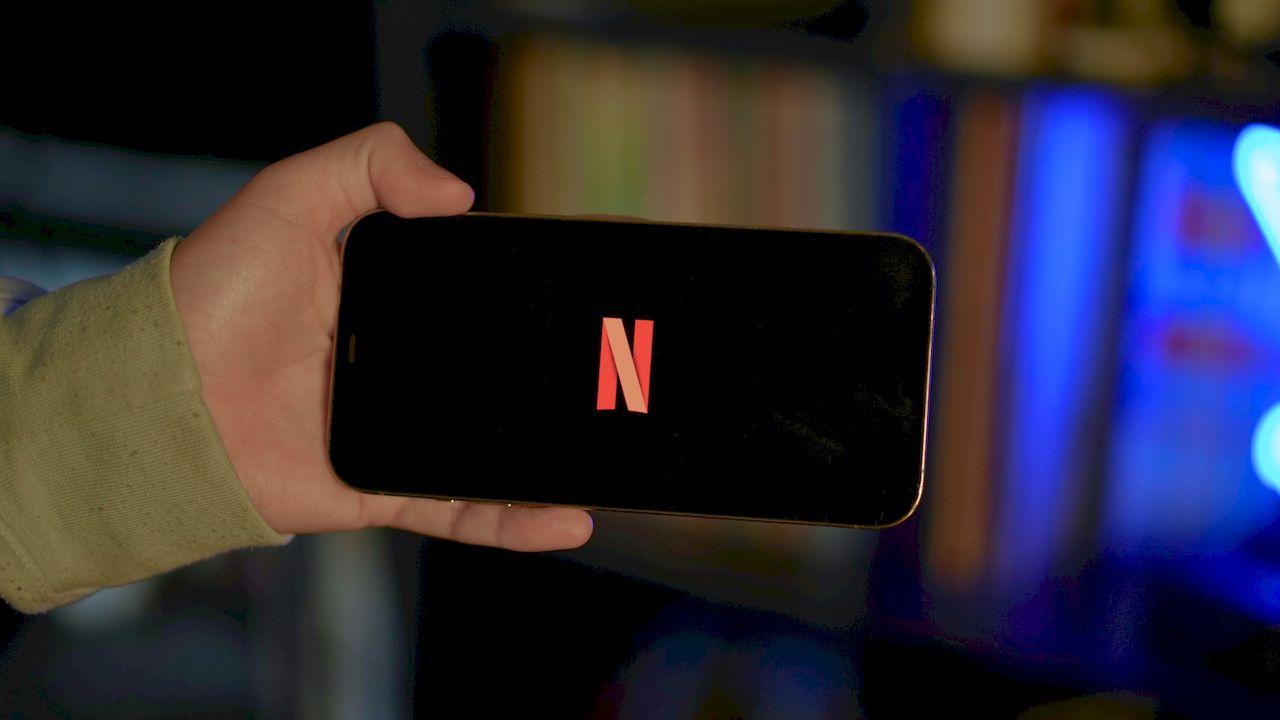 Una persona sujetando un móvil con el logo de Netflix en el centro