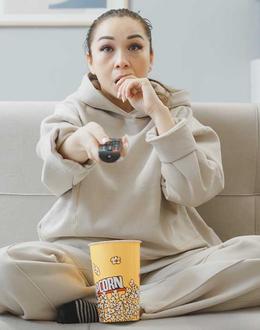 mujer viendo TV y comiendo palomitas