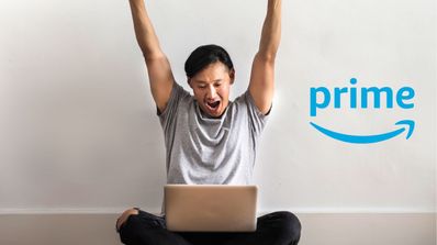 Un chico contento usando su portátil y logo Prime