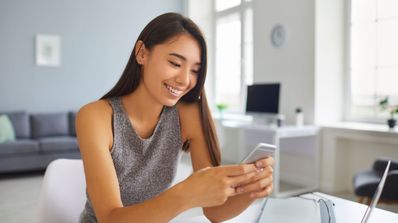 Una chica contenta sonríe mientras está usando el móvil