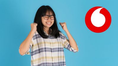 Una chica celebra una buena noticia y el logo de Vodafone al lado