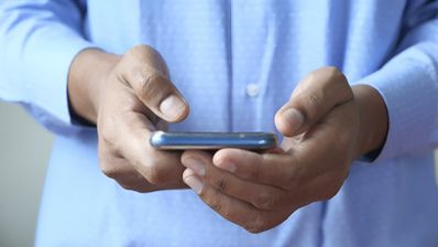 Primer plano de unas manos sujetando un teléfono móvil en posición horizontal para escribir un mensaje.