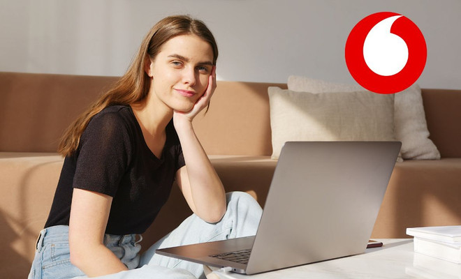 Una chica usando su ordenador portátil con el logo de Vodafone