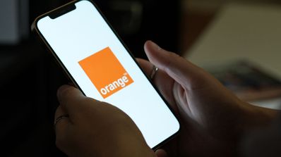 Sujetando un teléfono móvil con el logo cuadrado de Orange