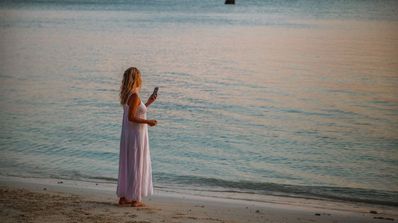 Una mujer en la playa trata de hacer una llamada