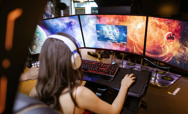 Una chica jugando en el ordenador con tres monitores