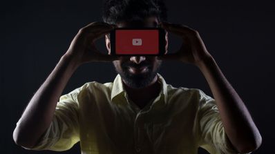 Un hombre posando con un móvil con el logo de YouTube en la cara