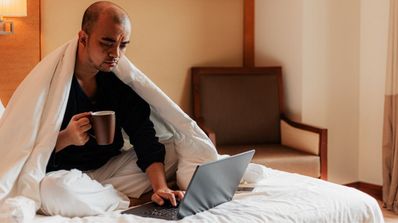 Un hombre está triste y usa su ordenador portátil en la cama
