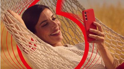 Una mujer sonríe mientras sujeta un móvil de Vodafone